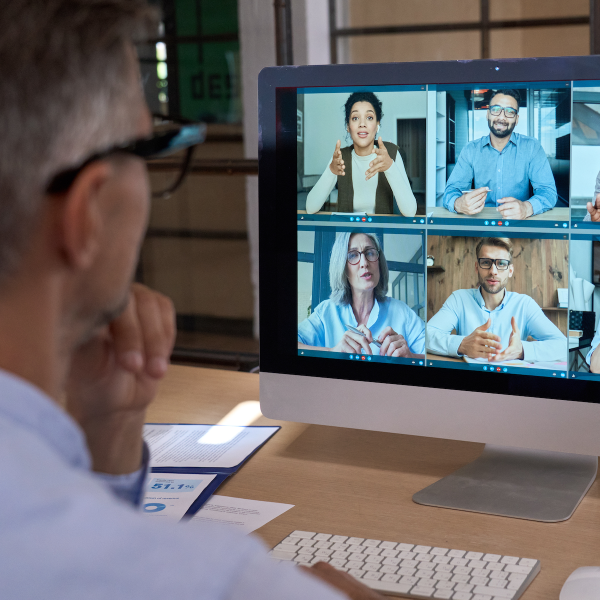 Businessman talking with team leading virtual meeting on computer. Over shoulder